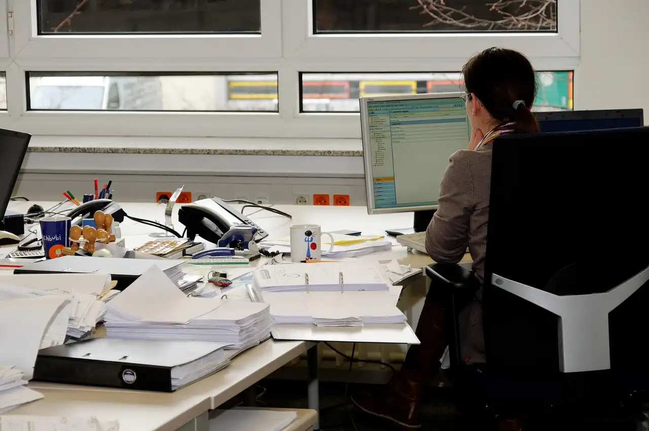 Mujer sentada en su puesto de trabajo mirando un ordenador